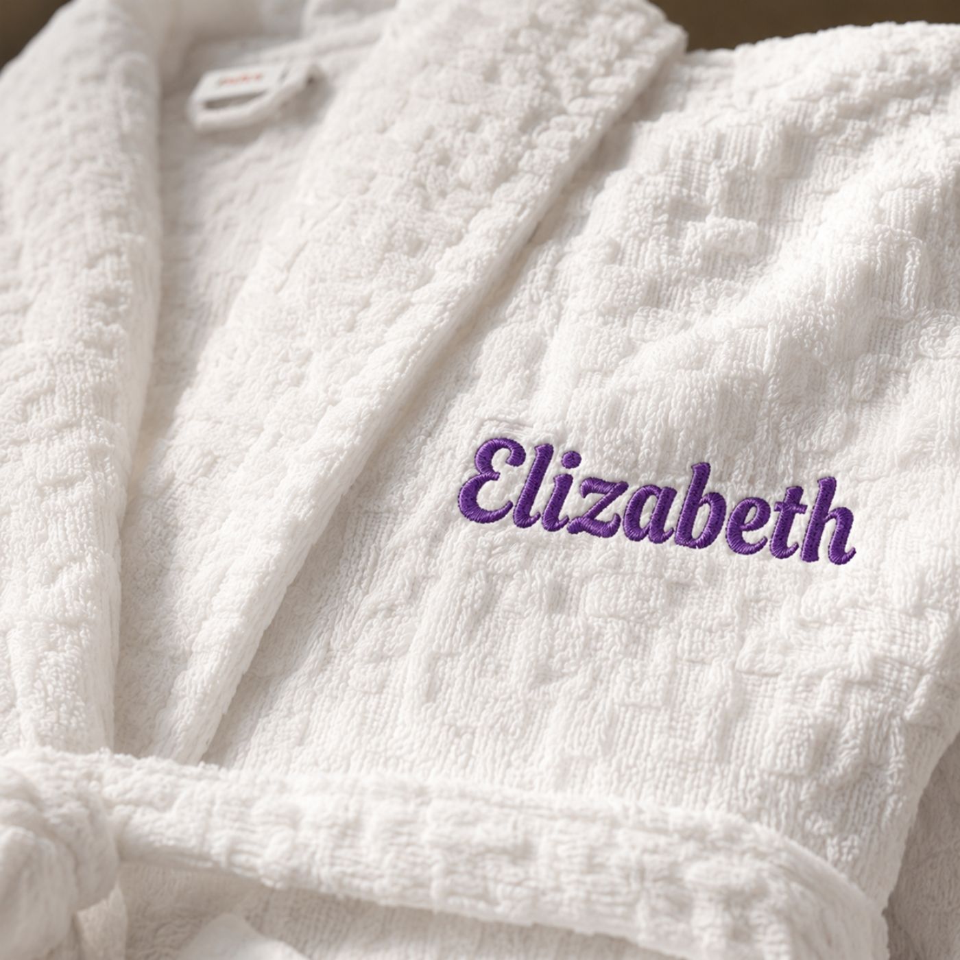 Close-up of embroidered name on white cotton bathrobe for her