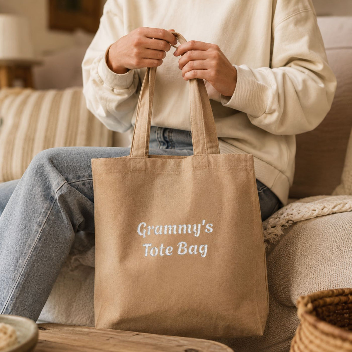 Personalized red cotton tote bag embroidered with "Nana's Tote Bag" held by grandmother in kitchen