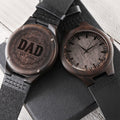 Hand holding an engraved wood watch showing DAD EST 2026 wreath design on the case back